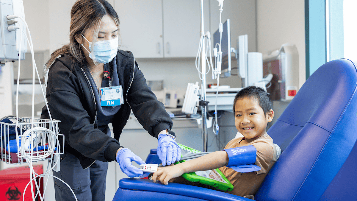 Young boy smiling while a nurse takes his vitals