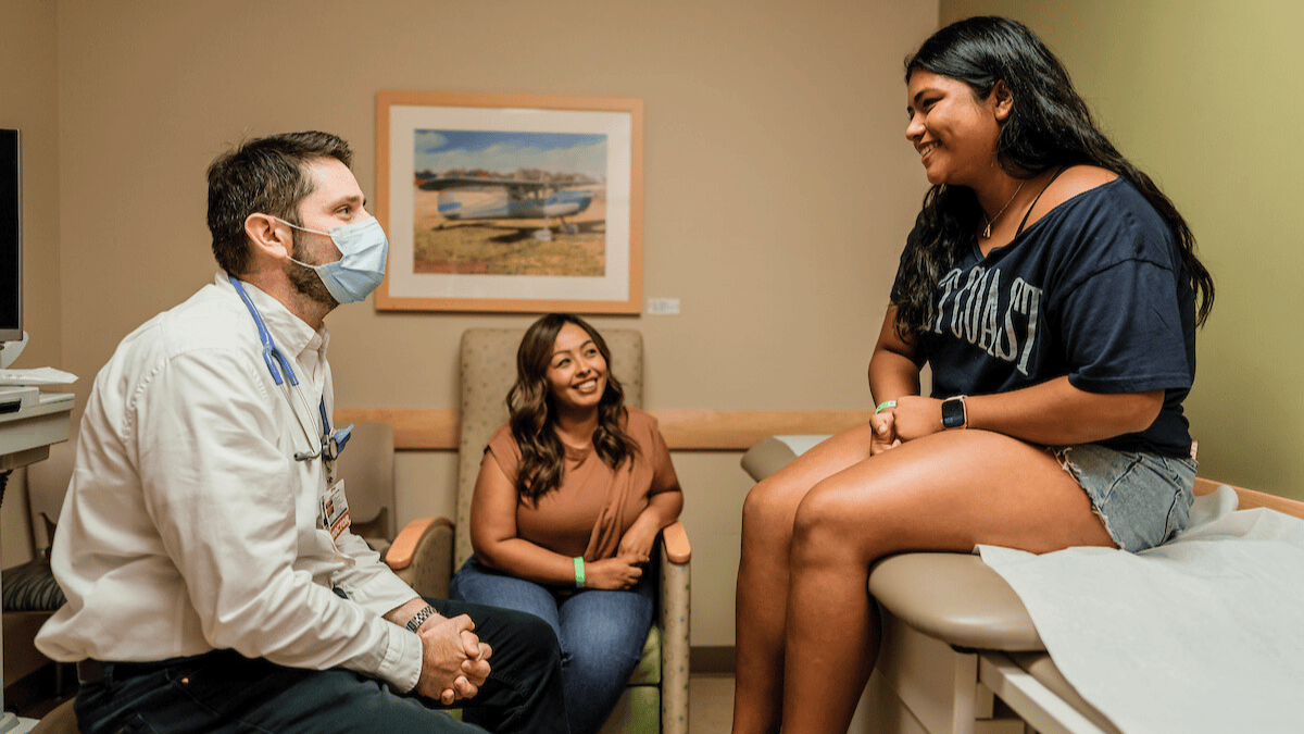 A gastroenterologist meets with a patient and parent