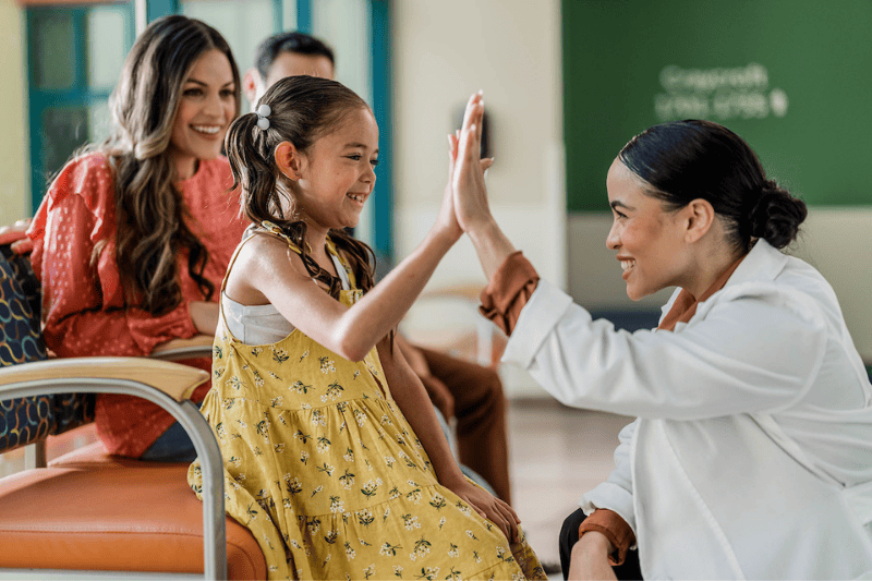 A young girl high fives a doctor