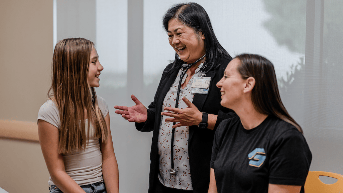 A nurse practitioner talks with a patient and parent