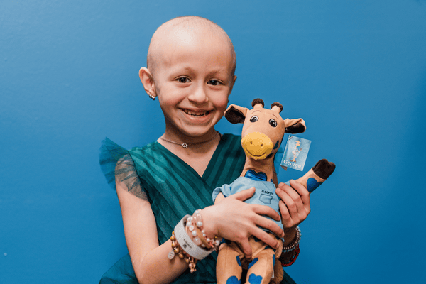 A young girl holds a plush giraffe toy