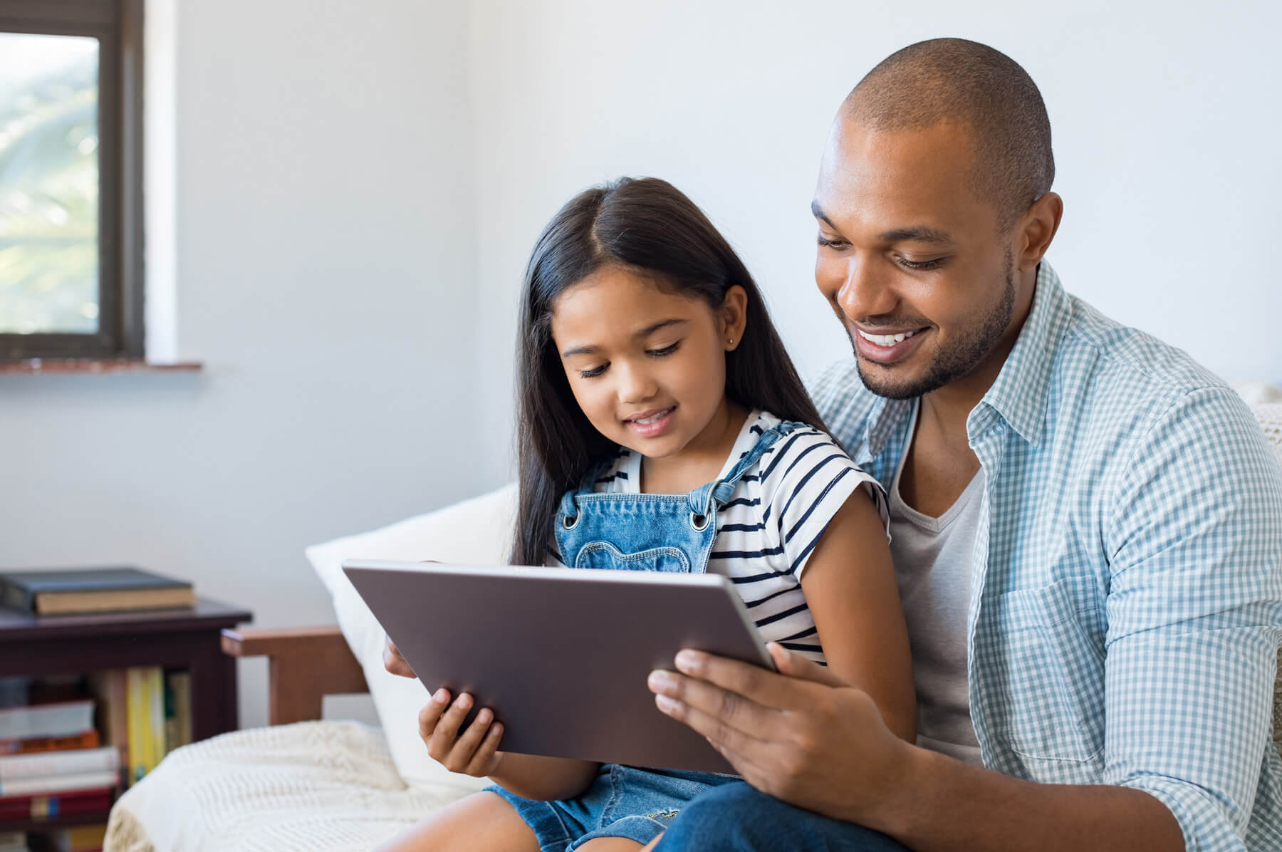 A father and daughter look at at tablet device