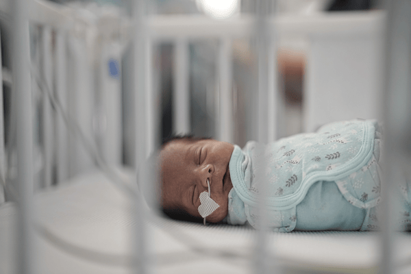 An infant in a NICU crib sleeps