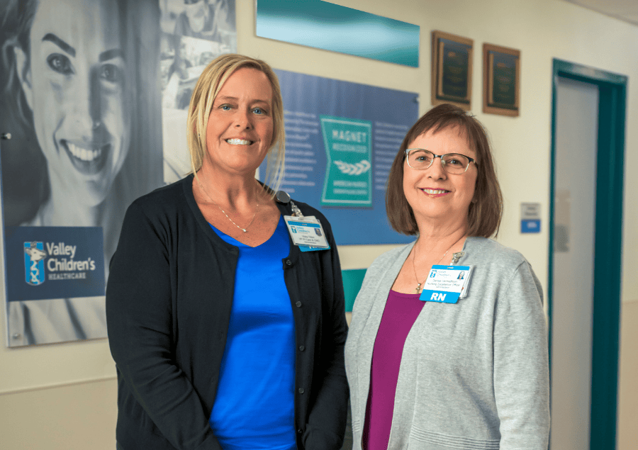 Two nursing leaders at Valley Children's smile next to the Nursing Wall at Valley Children's Hospital