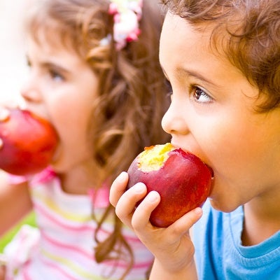 Two young children eat apples