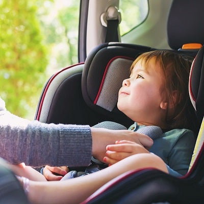 A young child is buckled into their car seat