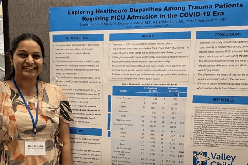 A Valley Children's pediatric resident smiles next to her research poster