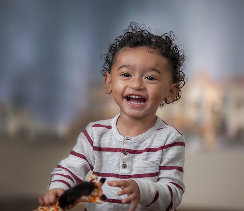 A small boy with curly hair smiles