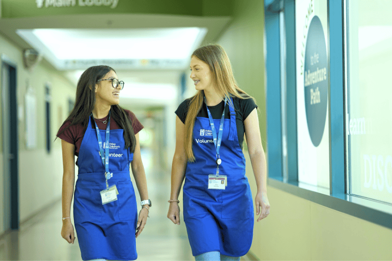 Two teenage volunteers walk down a hallway together at Valley Children's Hospital
