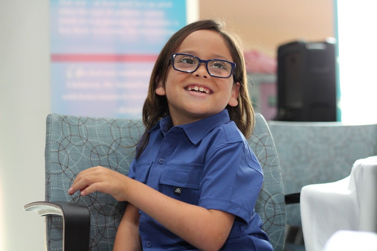 a little boy with glasses smiles