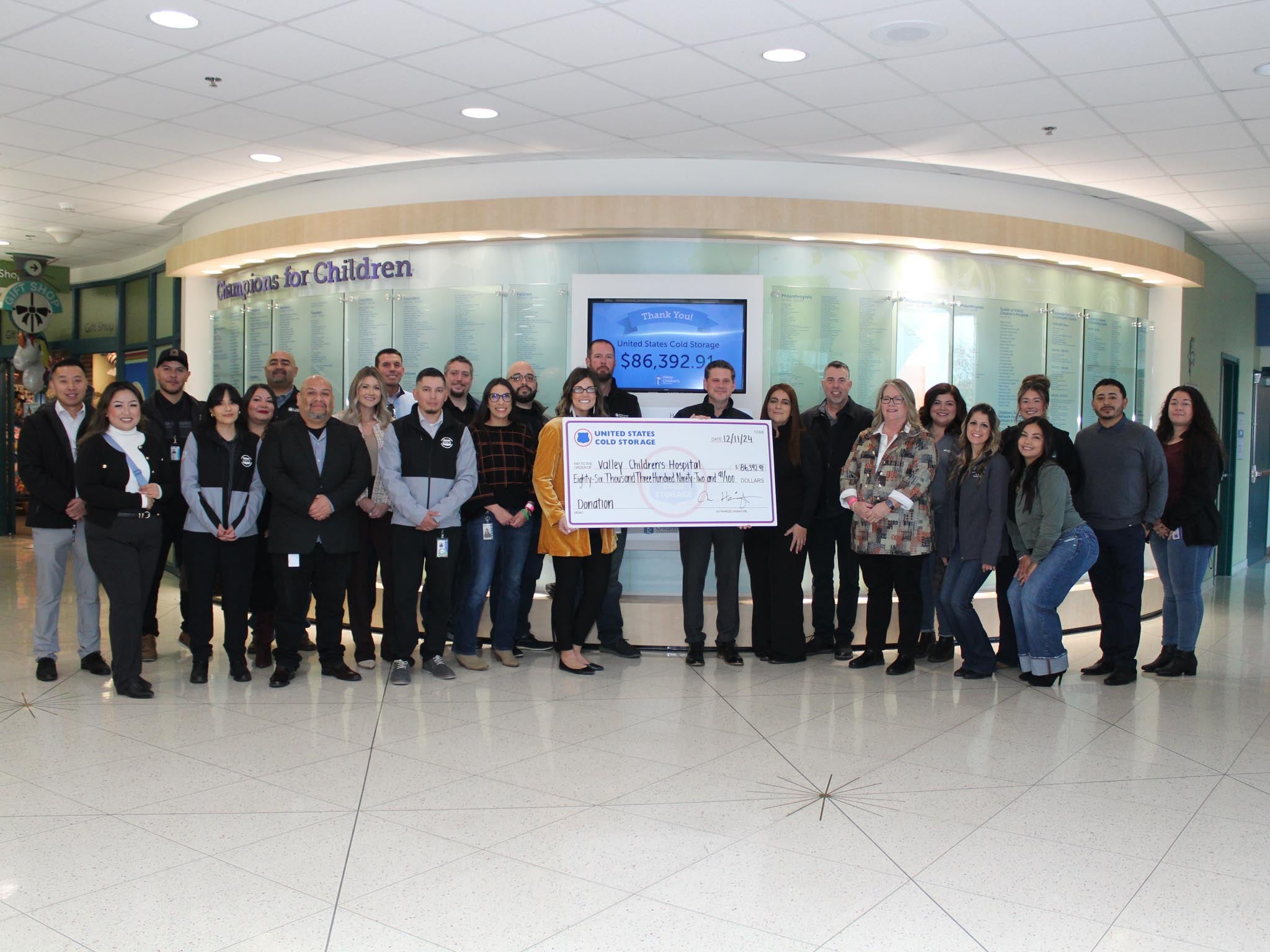 Group of people smiling holding large check