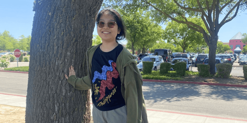 Faith smiles next to a tree