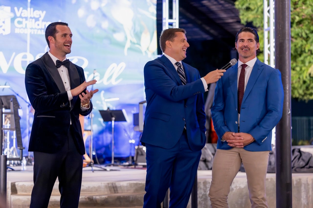 three men on stage smiling 