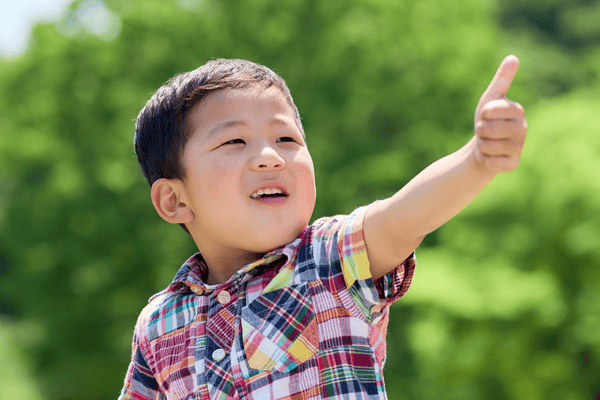 A young boy smiles and gives a thumbs up
