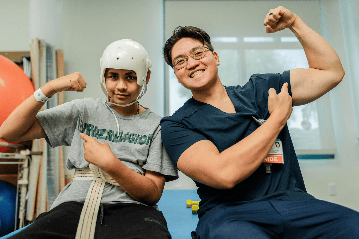 A rehab team aide poses and smiles with a patient
