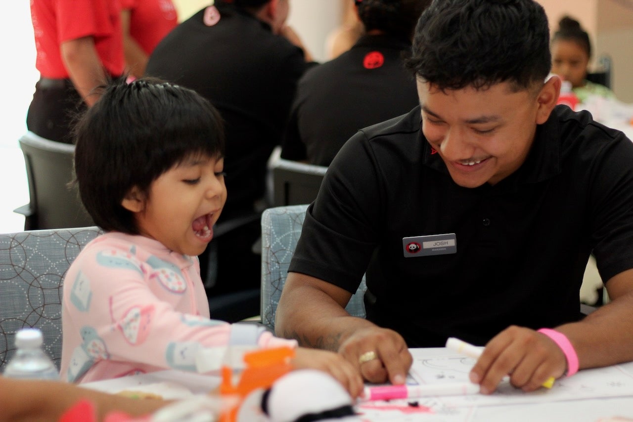 A Panda Express employee colors with a laughing child