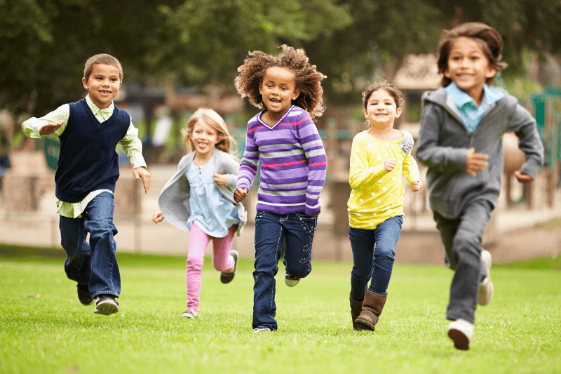 A group of young children smile and run