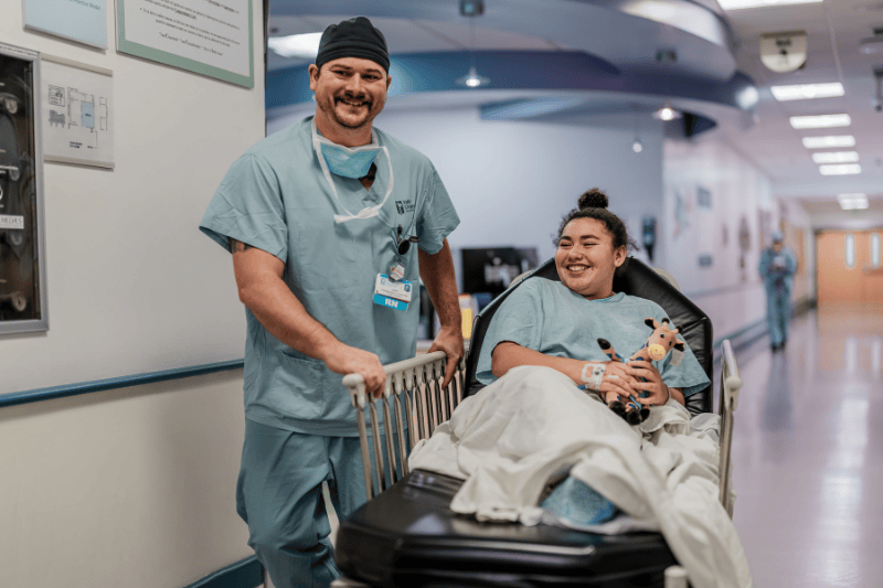 A surgical nurse guides a teen girl back to the OR