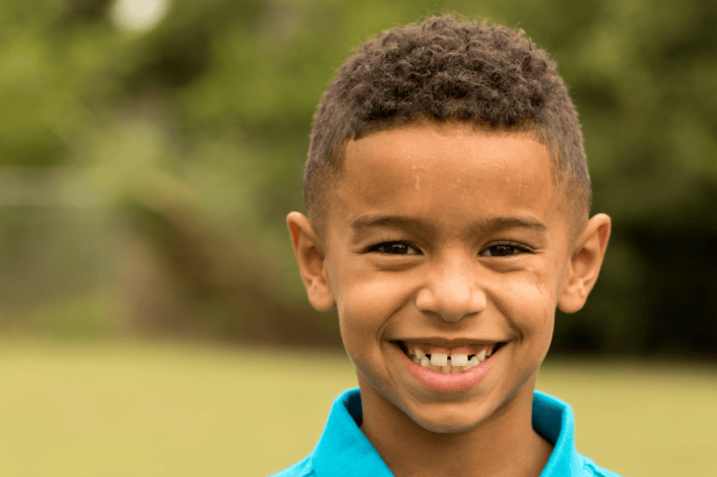 A young boy smiles directly at the camera
