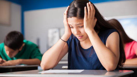 Child holding head looking distressed in a classroom 