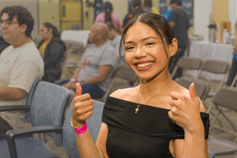 A teenage girl smiles and gives a thumbs up