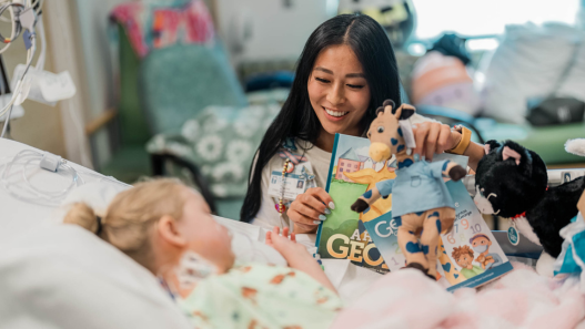 child life specialist Rachel reading book to a child in bed