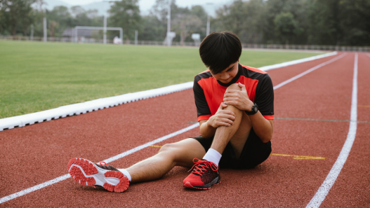 Teen holding injured leg on a track 