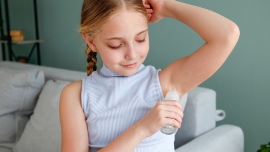 Teenage girl applying deodorant 