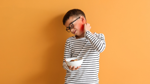 Child itching neck holding a bowl of nuts 