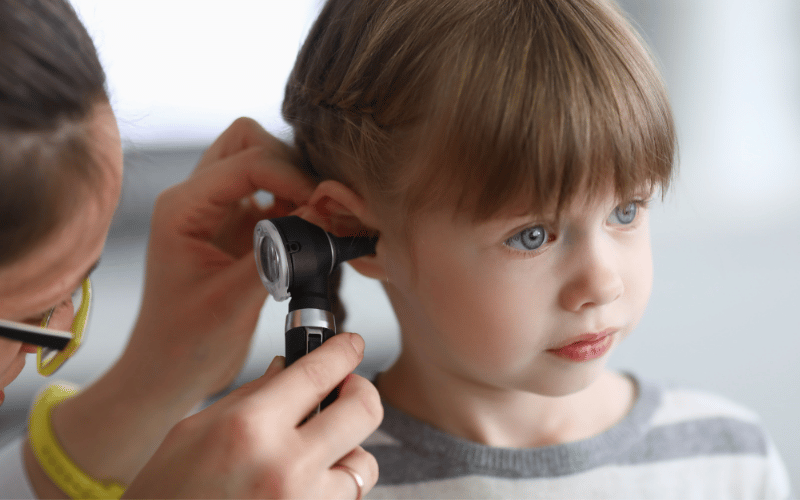A doctor uses an otoscope to look into a little girl's ear