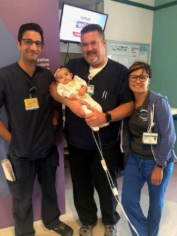 Healthcare providers holding baby and smiling