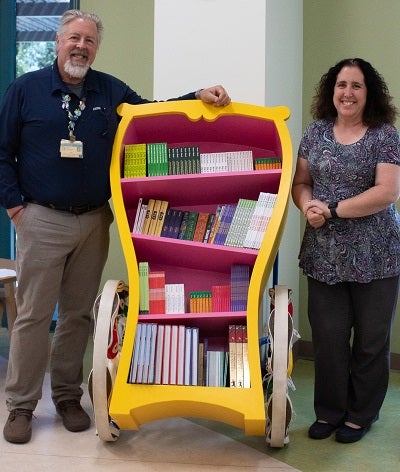 Valley Children's two medical librarians in front with George's Book Club cart