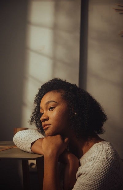 Teenage girl sitting and looking contemplatively out a window
