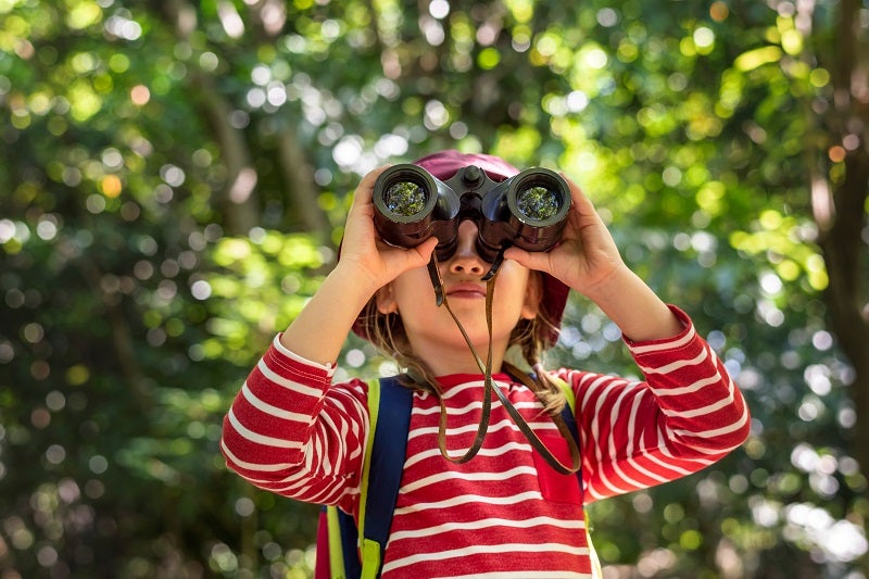 A young girl looks through a pair of binoculars