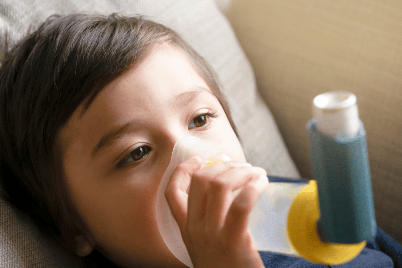 A young boy uses an inhaler