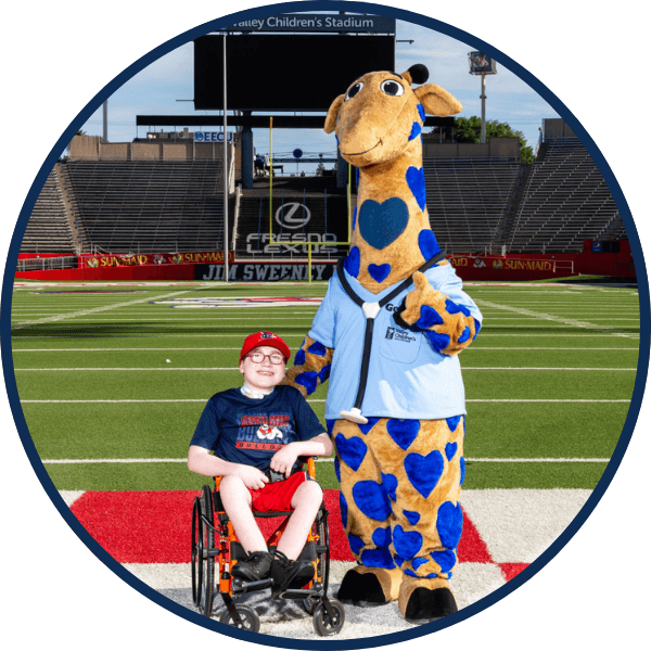 George the Giraffe poses with a patient in Valley Children's Stadium at Fresno State