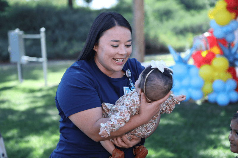 A nurse holds and smiles at a baby